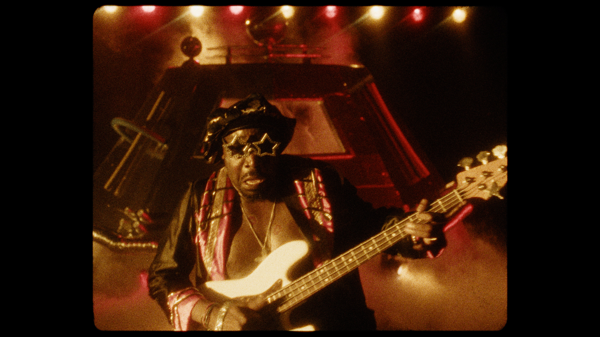 A man wearing star-shaped sunglasses playing the base.