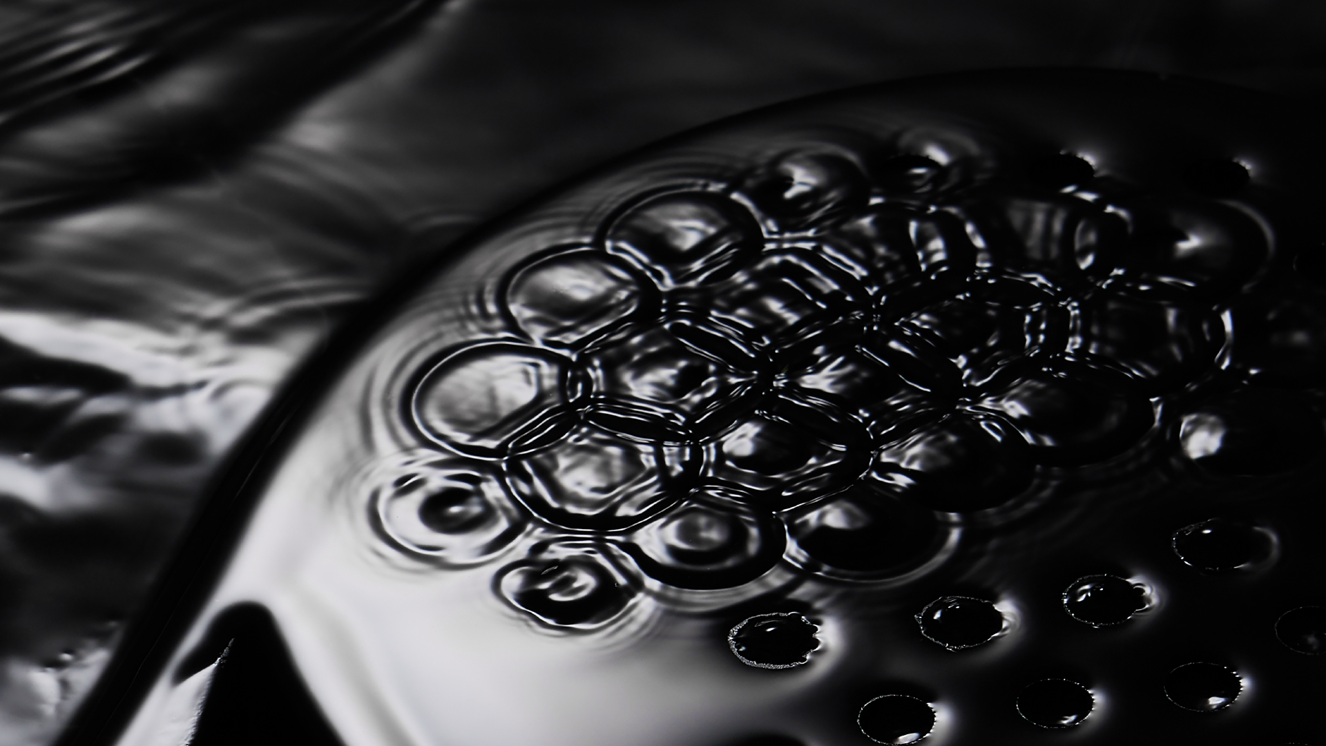 A padel racket submerged in black paint.