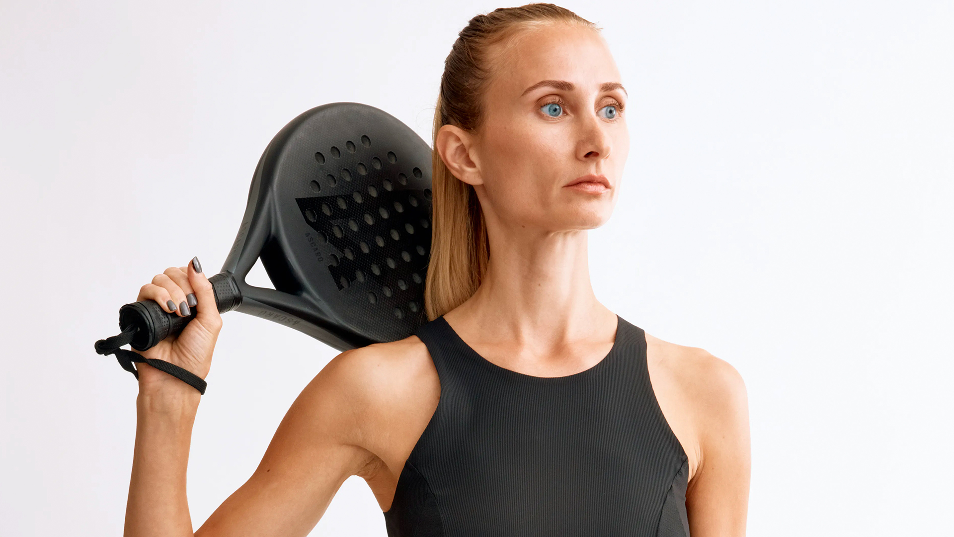 A woman holding a padel racket against her shoulder.