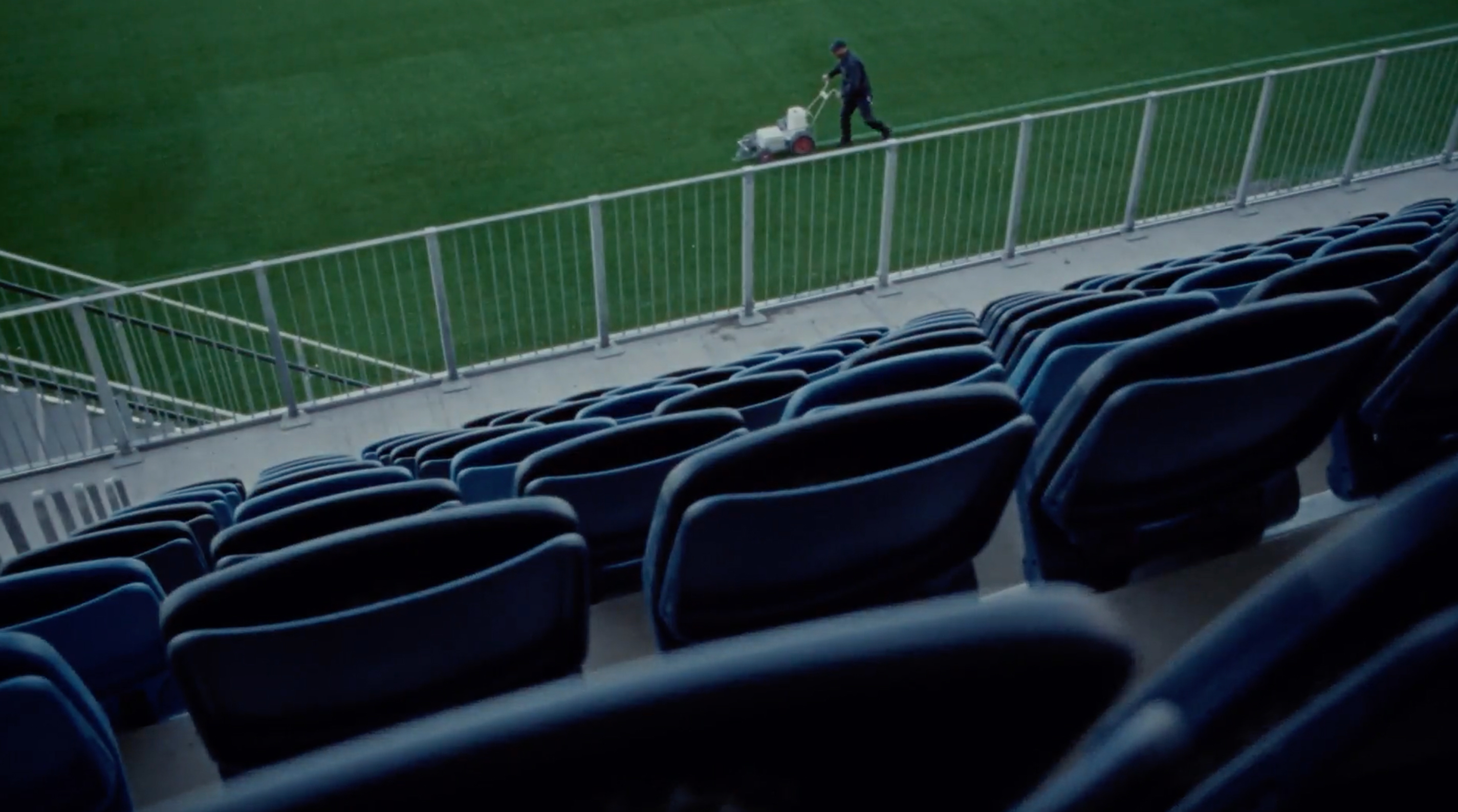 A janitor mowing the lawn at a football stadium.