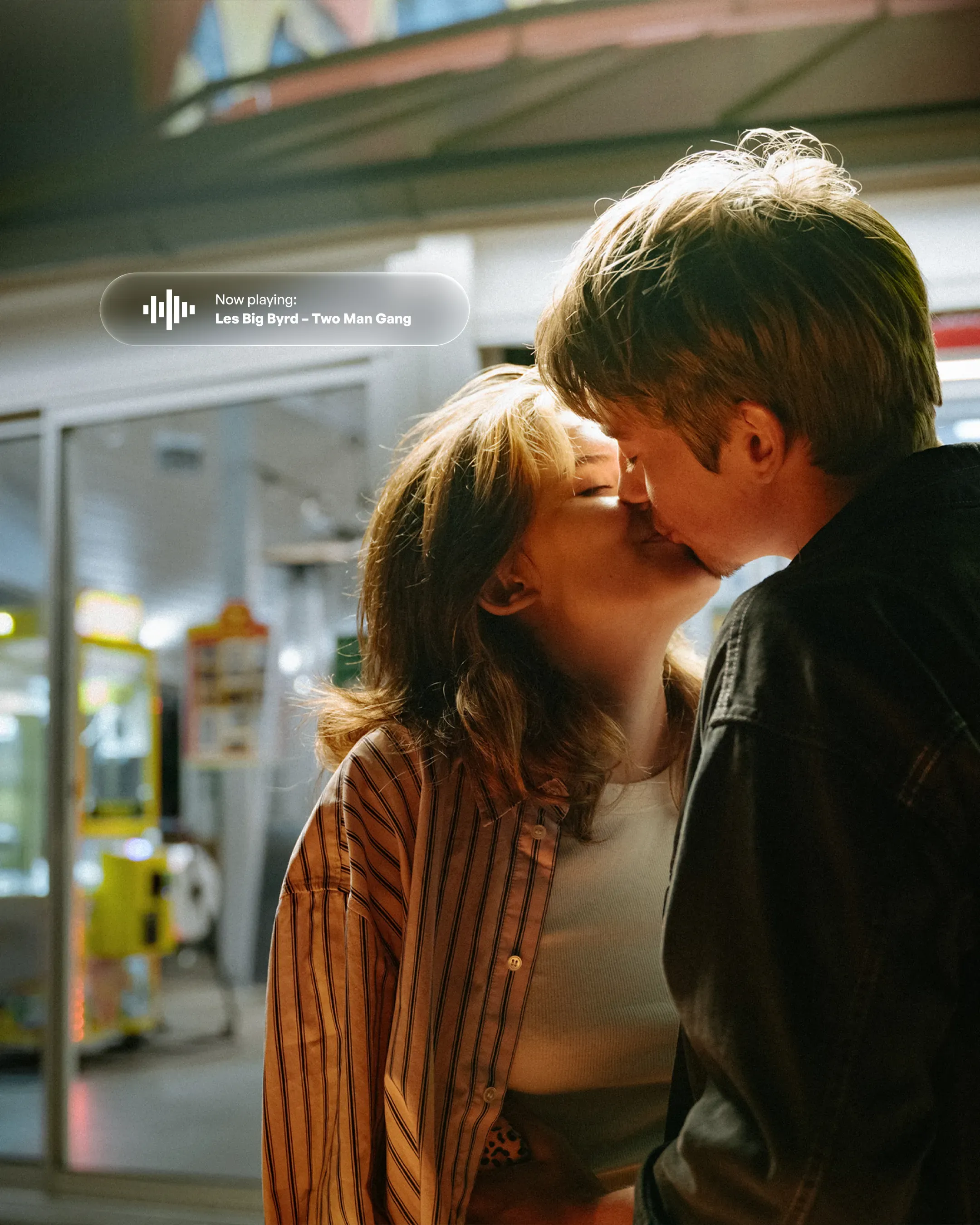 A young couple kissing next to a notification. Now playing: Les Big Byrd - Two Man Gang.